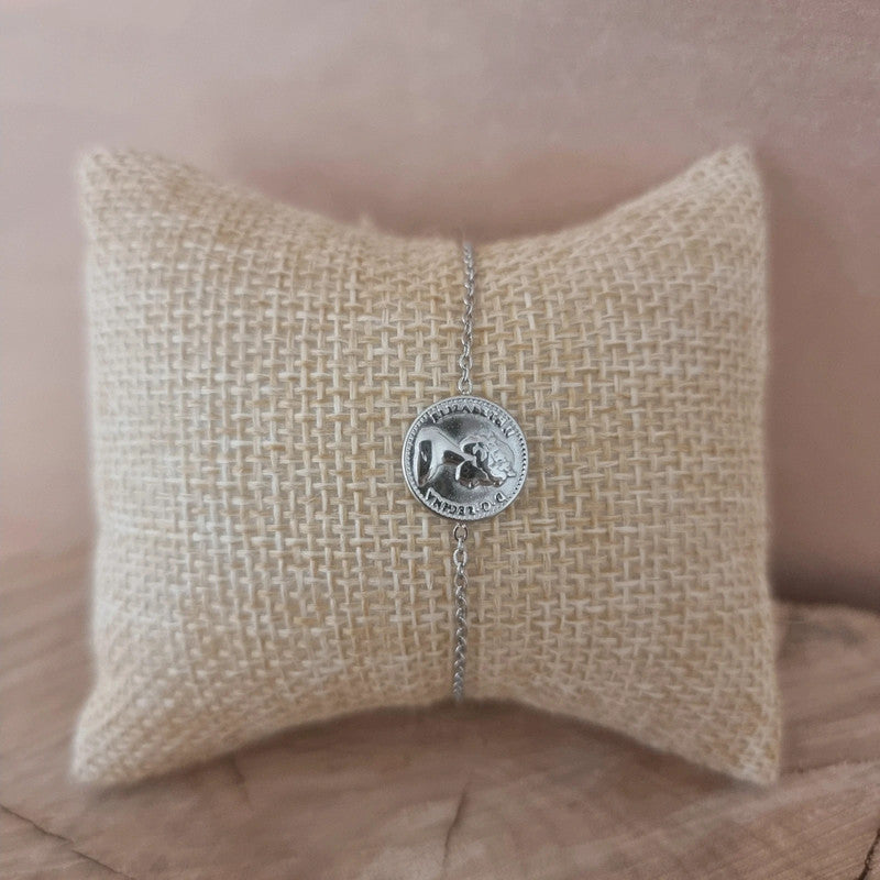 Bijou argenté élégant avec médaille Dos Pesos posé sur fond neutre