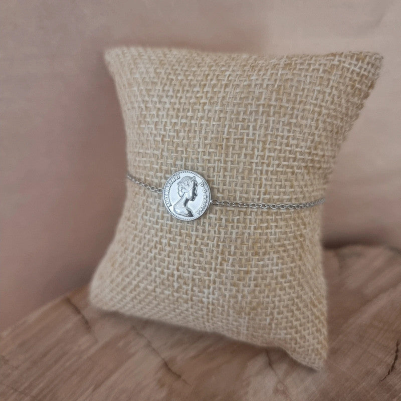 Bracelet argenté raffiné à maille fine porté au poignet avec médaille Dos Pesos