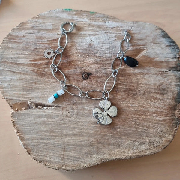 Bracelet original avec charms trèfle, fleur et perles décoratives.