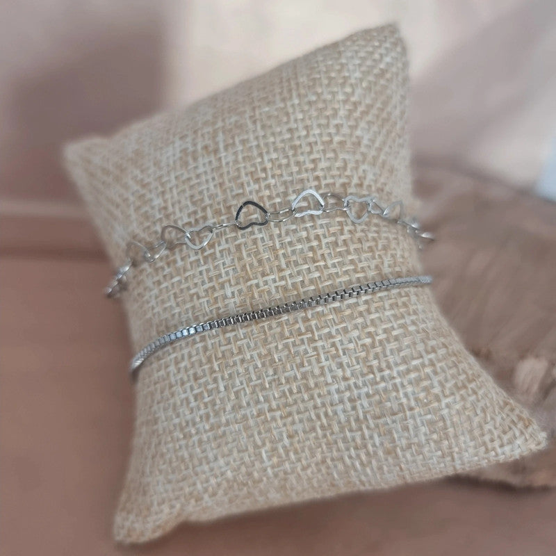 Ensemble de deux bracelets en acier inoxydable, design raffiné avec cœurs ajourés et chaîne fine intemporelle, posé sur fond neutre