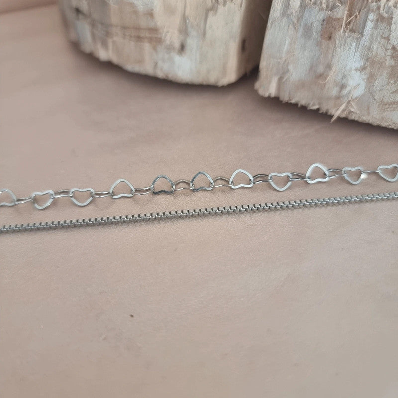 Duo de bracelets "Jenny" porté au poignet, mélange élégant de cœurs ajourés et de chaîne fine en acier inoxydable