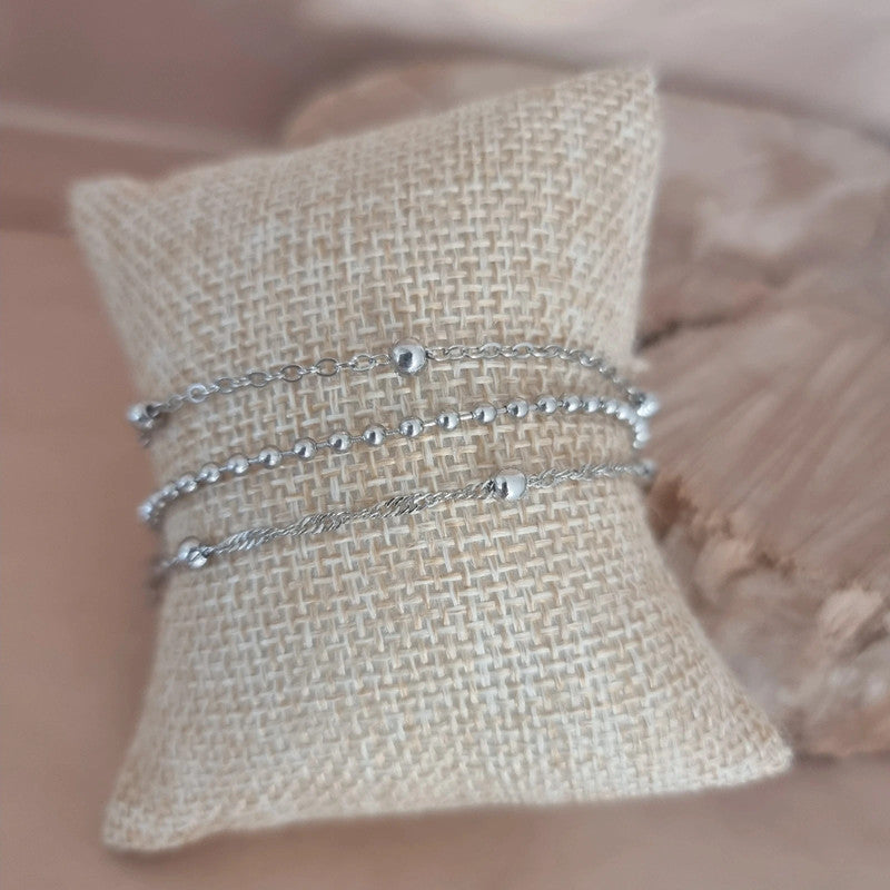 Trio de bracelets "Aurore" porté au poignet, accumulation élégante de mailles fines, perles et design contemporain en acier inoxydable