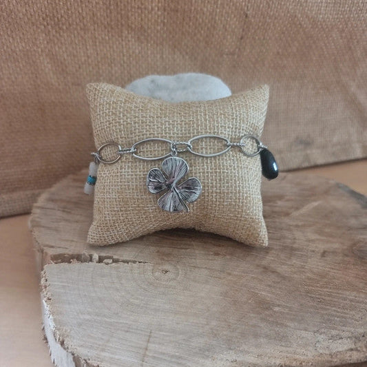 Bracelet argenté avec pendentif trèfle porte-bonheur et charms colorés.