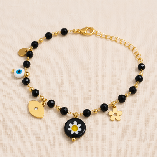 Bracelet femme en acier inoxydable doré avec perles de verre noires facettées, marguerite, cœur et œil porte-bonheur.