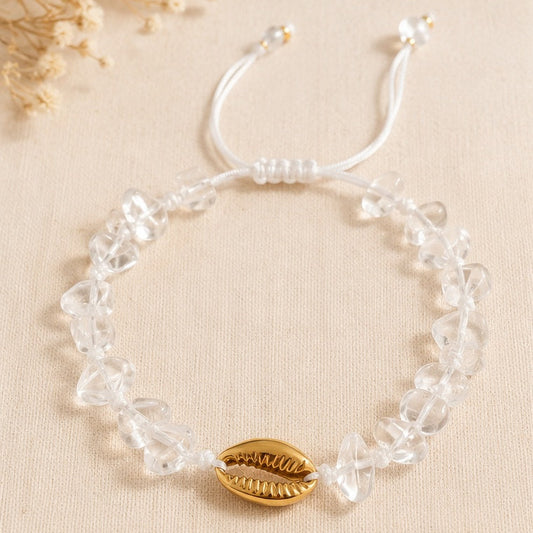 Bracelet blanc réglable avec pierres transparentes et coquillage doré.