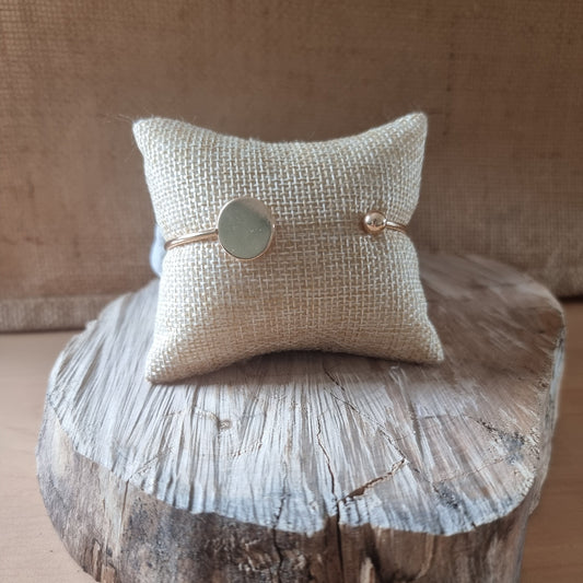 Bracelet doré fin avec médaillon rond présenté sur coussin en toile