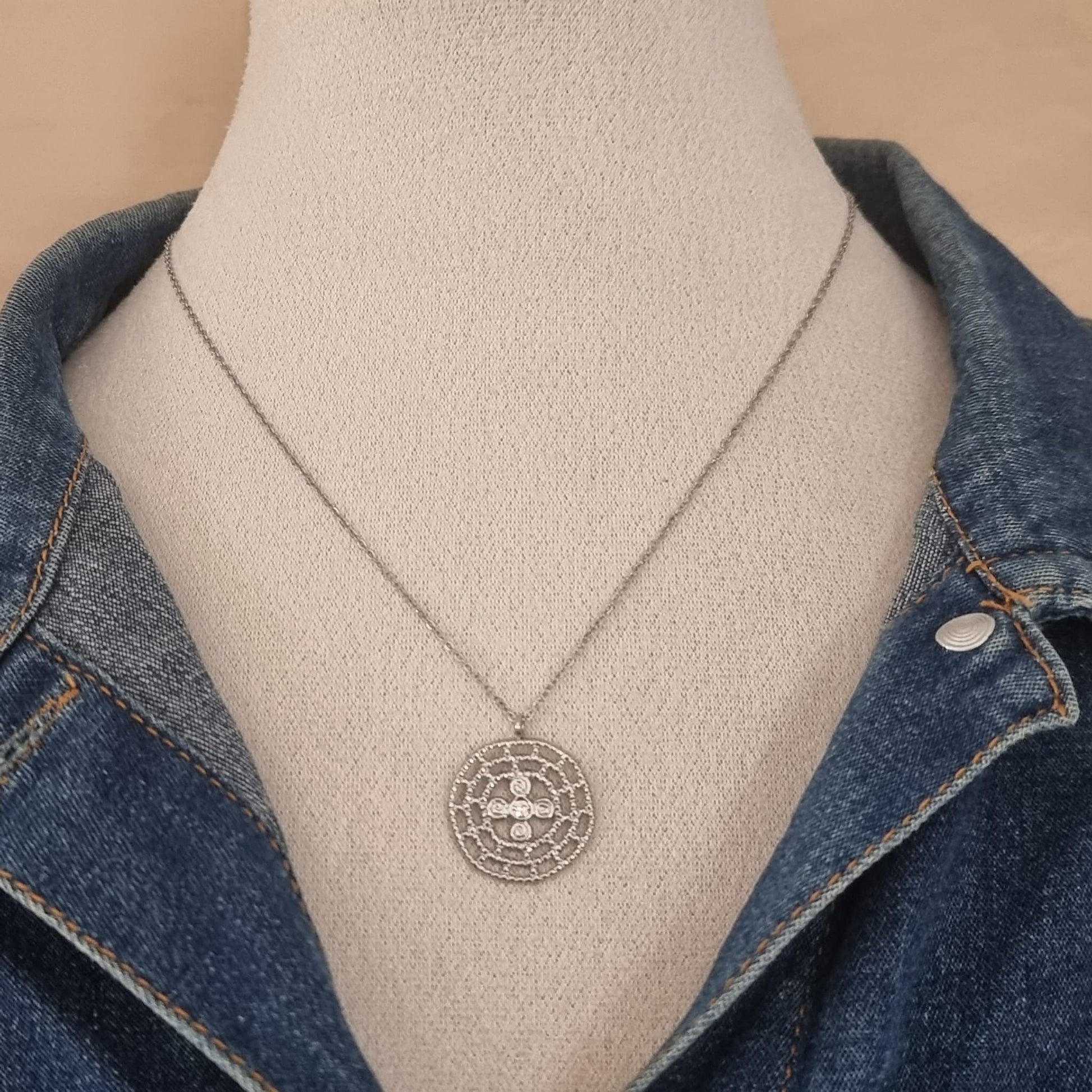 Collier argenté porté sur buste avec veste en jean.