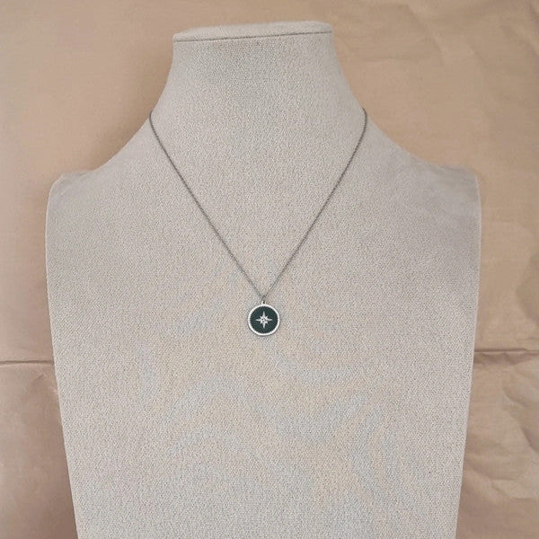 Collier symbolique vert et argent présenté sur une surface neutre.
